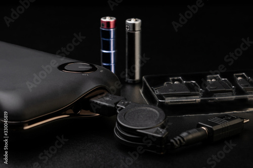 Powerbank for charging mobile devices and set of recharger heads on black background