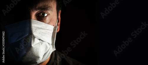 portrait of a man in a medical mask in a low key. a worldwide tragedy. COVID-19 virus pandemic warning photo