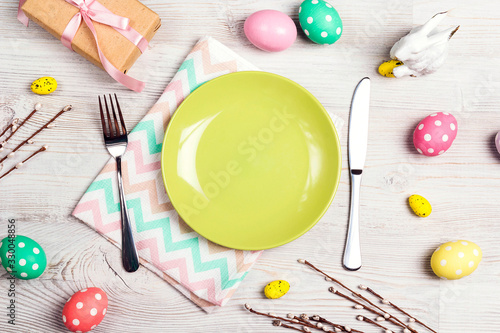 Table setting with cutlery and easter decorations on light wooden table. T
