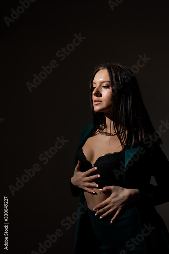 Studio photo of pretty brunette woman in twilight in bra looks into the distance