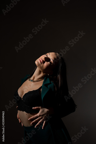 Studio photo of pretty brunette woman in twilight in bra looks into the distance
