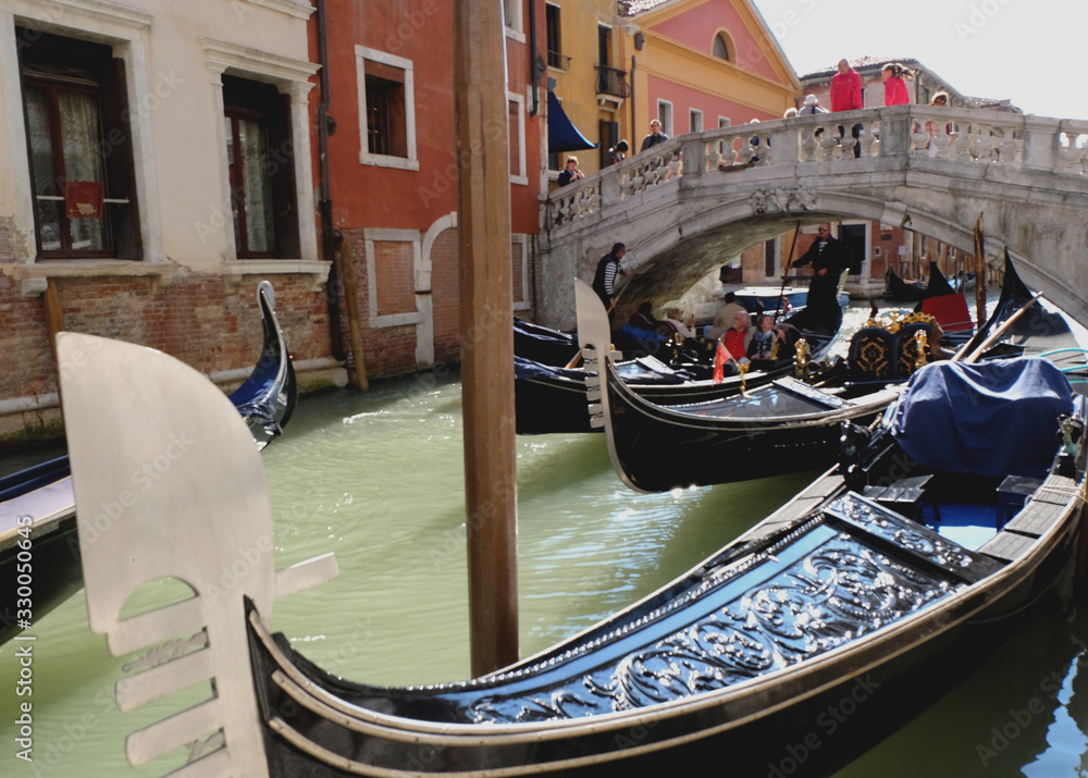Venetian gondolier punting gondola through canal waters of Venice Italy