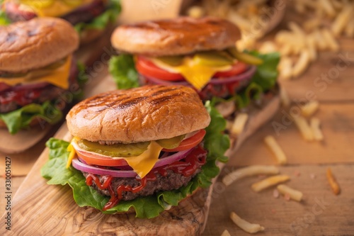 Juicy burgers on a wooden background with french fries. Home recipes, or cafe. Calorie and junk food.