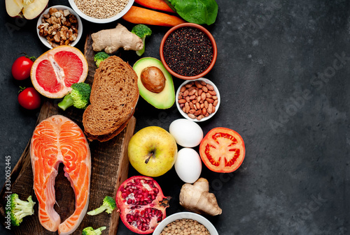 Selection of healthy food: salmon, fruits, seeds, cereals, superfoods, vegetables, leafy vegetables on a stone background with copy space for your text.Healthy food for people 