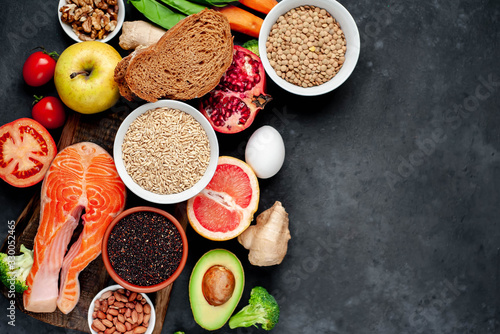 Selection of healthy food: salmon, fruits, seeds, cereals, superfoods, vegetables, leafy vegetables on a stone background with copy space for your text.Healthy food for people 