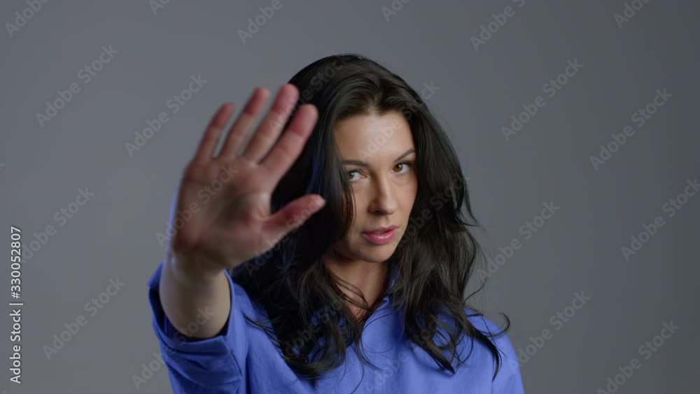 Mature woman disapproving with NO hand sign gesture. Denying, rejecting, disagree, portrait of beautiful adult lady on grey background Mature woman disapproving with NO hand sign gesture. Denying, rejecting, disagree, portrait of beautiful adult lady on grey background