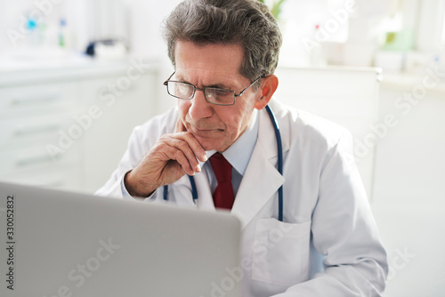 Senior doctor working with a laptop in doctor’s office © gpointstudio
