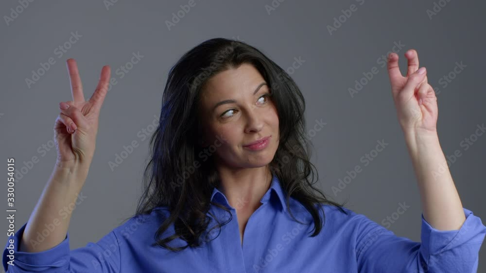 Pretty woman showing with hands and two fingers like quotes gesture, bend fingers isolated over grey background. Very funny, irony and sarcasm concept. Pretty woman showing with hands and two fingers like quotes gesture, bend fingers isolated over grey background. Very funny, irony and sarcasm concept.