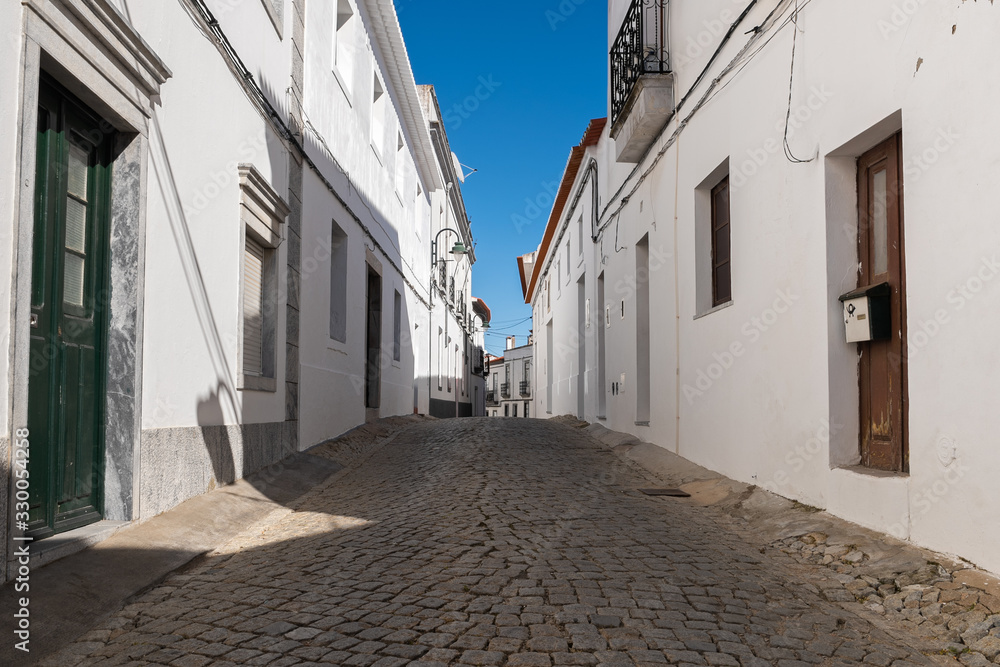 Narrow street with traditional white houses of an old town in the south of Portugal