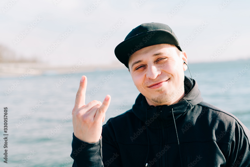 a young guy in sports black clothes sits on a pier near the lake on a Sunny spring day a young guy in sports black clothes sits on a pier near the lake on a Sunny spring day