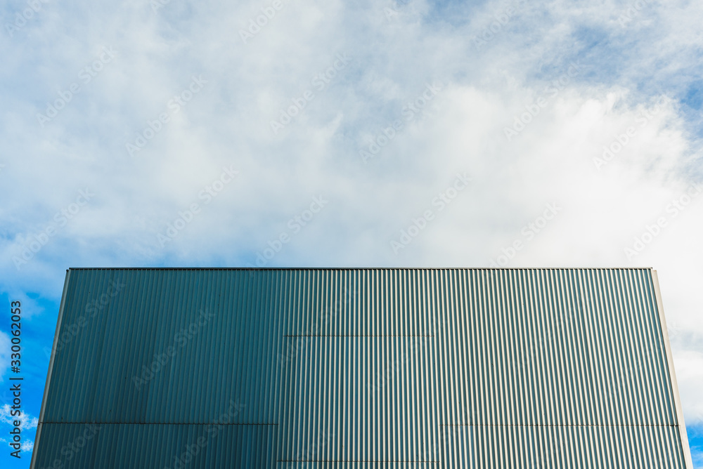 Aluminum wall at the back of a smooth windowless building and blue sky. Aluminum wall at the back of a smooth windowless building and blue sky.