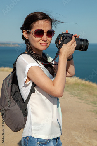 Thin girl with camera in nature, by the sea