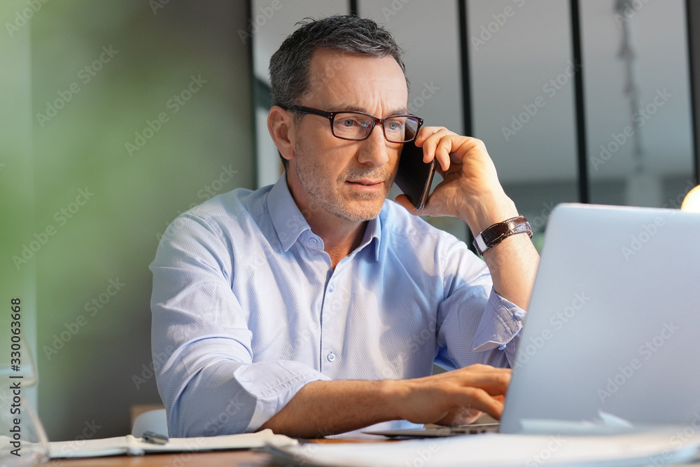 Business manager working in office talking on phone Business manager working in office talking on phone