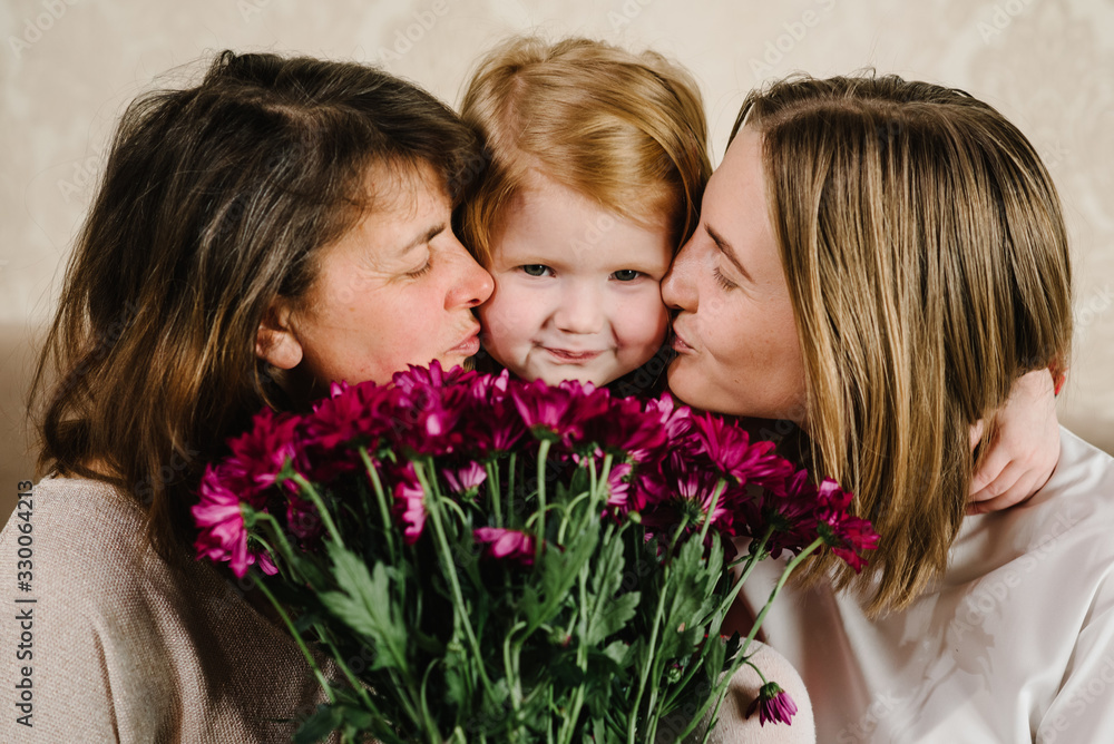 Portrait mother with flowers, grandmother kissing and hugging granddaughter and spend time together. International Women's Day. Happy Mother's Day. Holiday concept. Three generations of women. Portrait mother with flowers, grandmother kissing and hugging granddaughter and spend time together. International Women's Day. Happy Mother's Day. Holiday concept. Three generations of women.