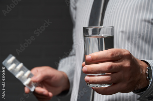 Businessman closeup portrait, he standing and posing with pills, health and medication concept, dark wall background