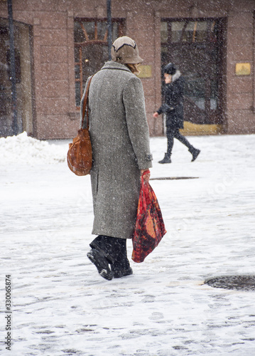 Woman walking down the street in winter day in motion blur
