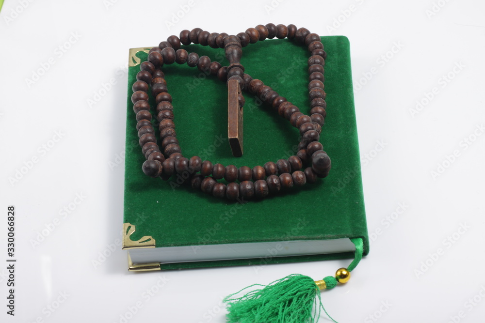 wooden praying beads on a green holy book isolated on white background wooden praying beads on a green holy book isolated on white background