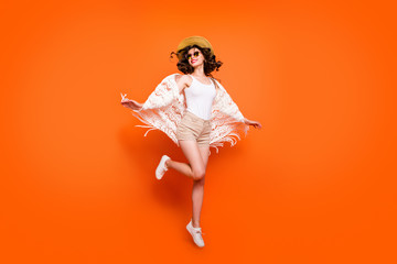 Full length photo of funny lady summer time jumping high enjoy great resort views wear stylish sun hat specs stylish white lace beach cape shorts isolated orange background