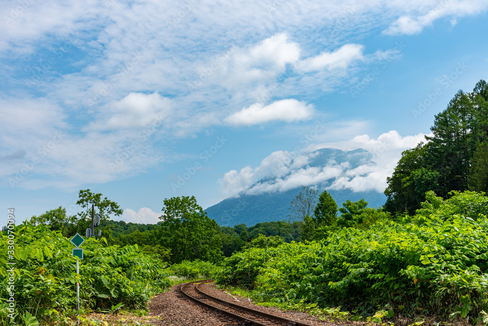 Hakodate main line railroad at Town Niseko in springtime sunny day with Mount Yotei in the background. Shiribeshi Subprefecture, Hokkaido, Japan