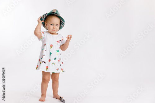 Portrait of a little cute girl wearing summer dress, blue checkered hat and fashion sunglasses isolated on white background. Concept of travel and summertime.