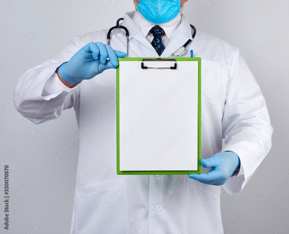 male doctor in a white medical coat and blue latex gloves holds a tablet with a paper clip with a white blank sheet male doctor in a white medical coat and blue latex gloves holds a tablet with a paper clip with a white blank sheet