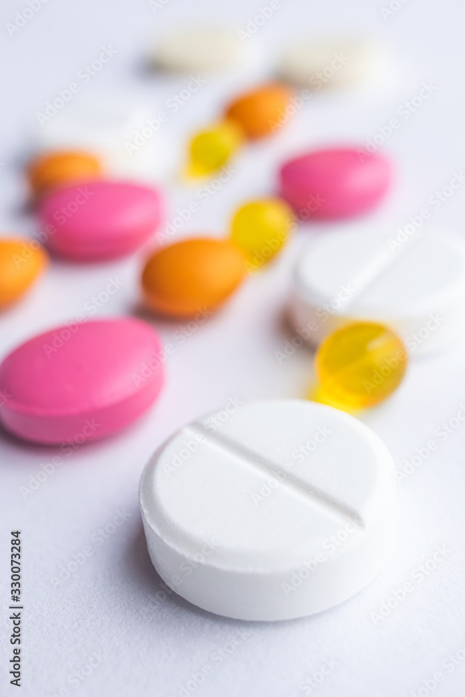 Multi-colored pills on a light background. The concept of protection against viruses, medicine, prevention and treatment of diseases. Macro, minimalism. Multi-colored pills on a light background. The concept of protection against viruses, medicine, prevention and treatment of diseases. Macro, minimalism.