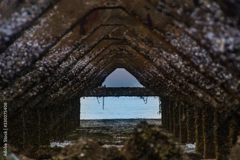 View under at Broken old structure remains of pier in the during beautiful twilight in the sea. View under at Broken old structure remains of pier in the during beautiful twilight in the sea.