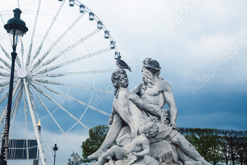 Paris touristic square with garden, sculpture and big ferris wheel on cloudy sky