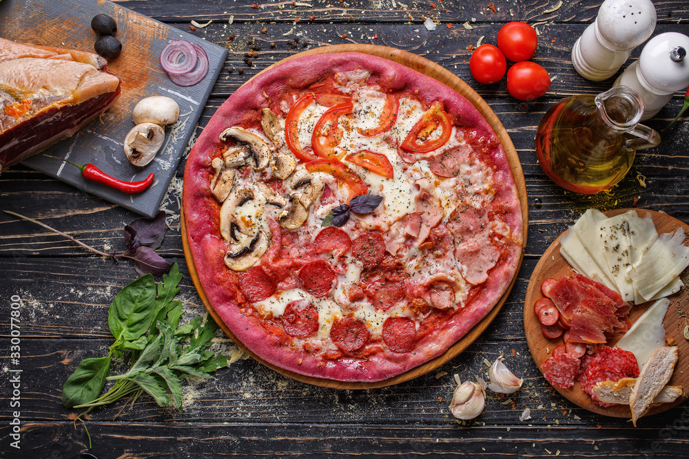 Food ingredients and spices for cooking mushrooms, tomatoes, cheese, onion, oil, pepper, salt, basil, ham, garlic and delicious italian pizza on wooden background.