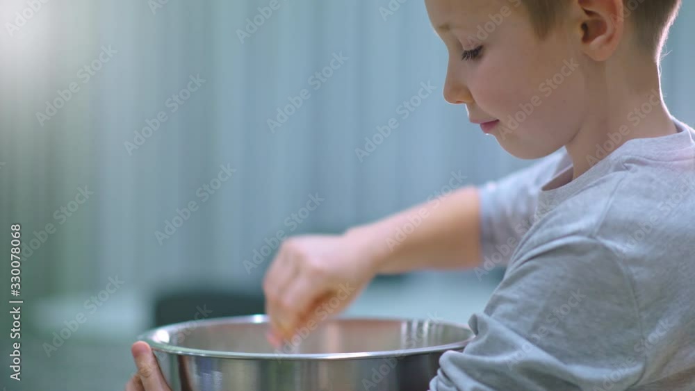 Boy cooking at the kitchen. White boy stirring dough for a cookie. Kid is mixing ingredients for a cake in the steel bowl. 8 years old child cooking food at home. Real time 4k footage Boy cooking at the kitchen. White boy stirring dough for a cookie. Kid is mixing ingredients for a cake in the steel bowl. 8 years old child cooking food at home. Real time 4k footage