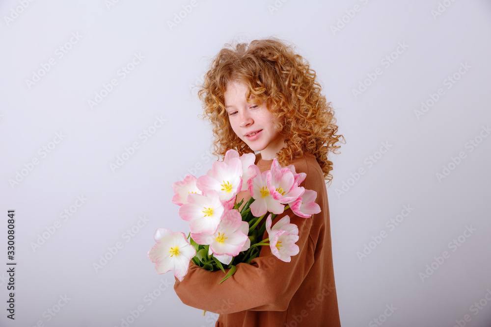 beautiful red haired curly haired teen girl with a bouquet of spring pink tulips on a white background