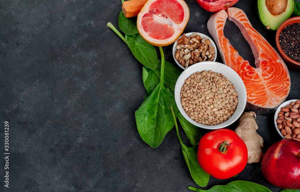 Selection of healthy food: salmon, fruits, seeds, cereals, superfoods, vegetables, leafy vegetables on a stone background with copy space for your text. Healthy food for people. Selection of healthy food: salmon, fruits, seeds, cereals, superfoods, vegetables, leafy vegetables on a stone background with copy space for your text. Healthy food for people.