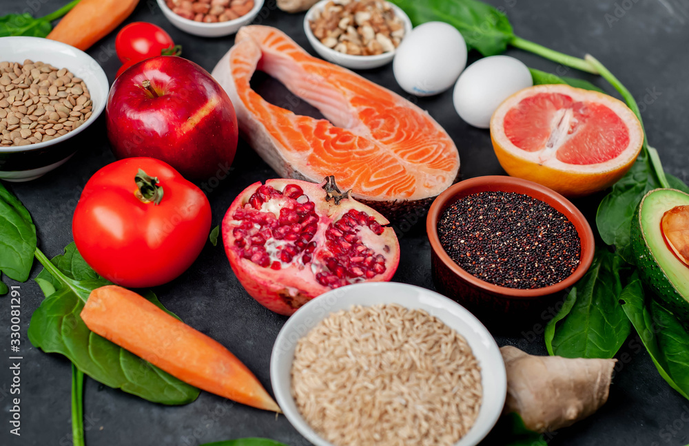 Selection of healthy food: salmon, fruits, seeds, cereals, superfoods, vegetables, leafy vegetables on a stone background. Healthy food for people. Selection of healthy food: salmon, fruits, seeds, cereals, superfoods, vegetables, leafy vegetables on a stone background. Healthy food for people.