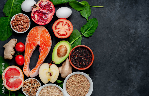Selection of healthy food: salmon, fruits, seeds, cereals, superfoods, vegetables, leafy vegetables on a stone background with copy space for your text. Healthy food for people.