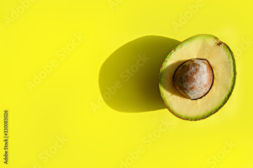Half of avocado on a yellow background. Top view. Copy, empty space for text.