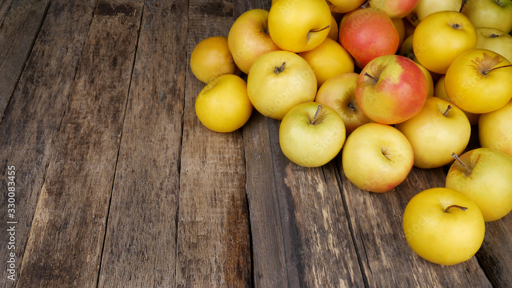 A lot of ripe yellow apples on a old wooden table. Place for text.