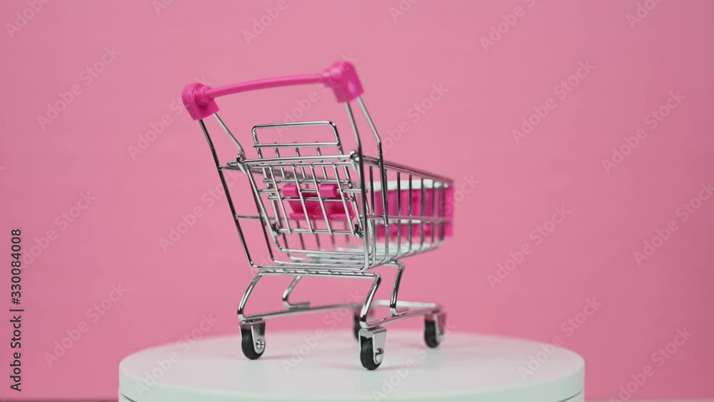 empty shopping cart rotating on pink background consumer online spending concept empty shopping cart rotating on pink background consumer online spending concept