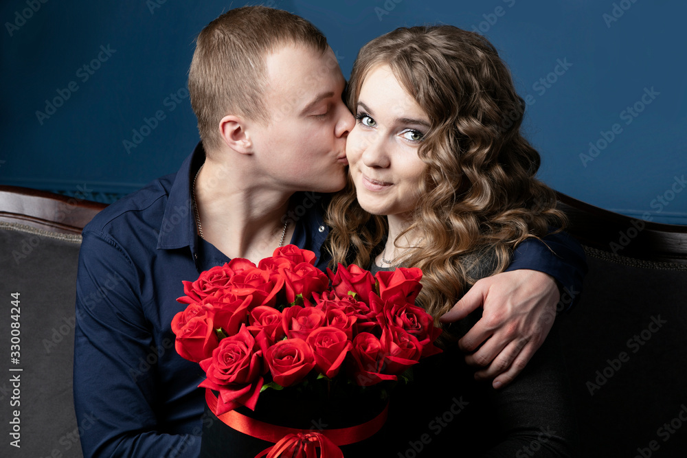The guy and the girl with a bouquet of roses. A young couple. Lovers. A man kisses a beautiful woman. The guy and the girl with a bouquet of roses. A young couple. Lovers. A man kisses a beautiful woman.