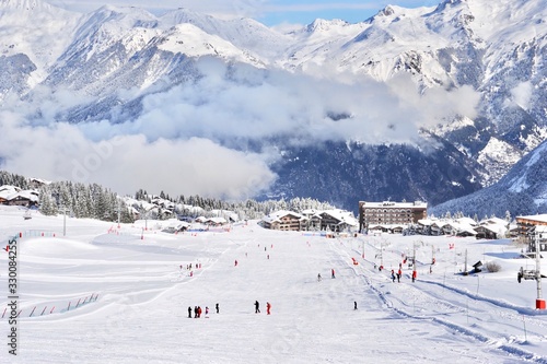 Ski resort with wide  ski slope and skiers 
