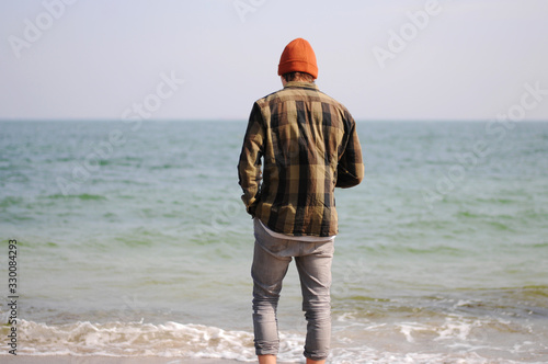 A man stands with his back to the sea. Views of the ocean. The man resting on the sea.