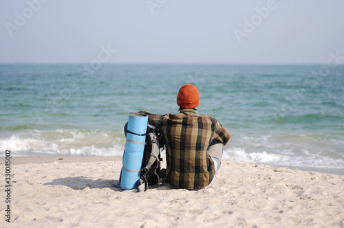 Man sits on the seashore and relaxes. Looks into the boundless blue distance. Vacation, beach vacation.