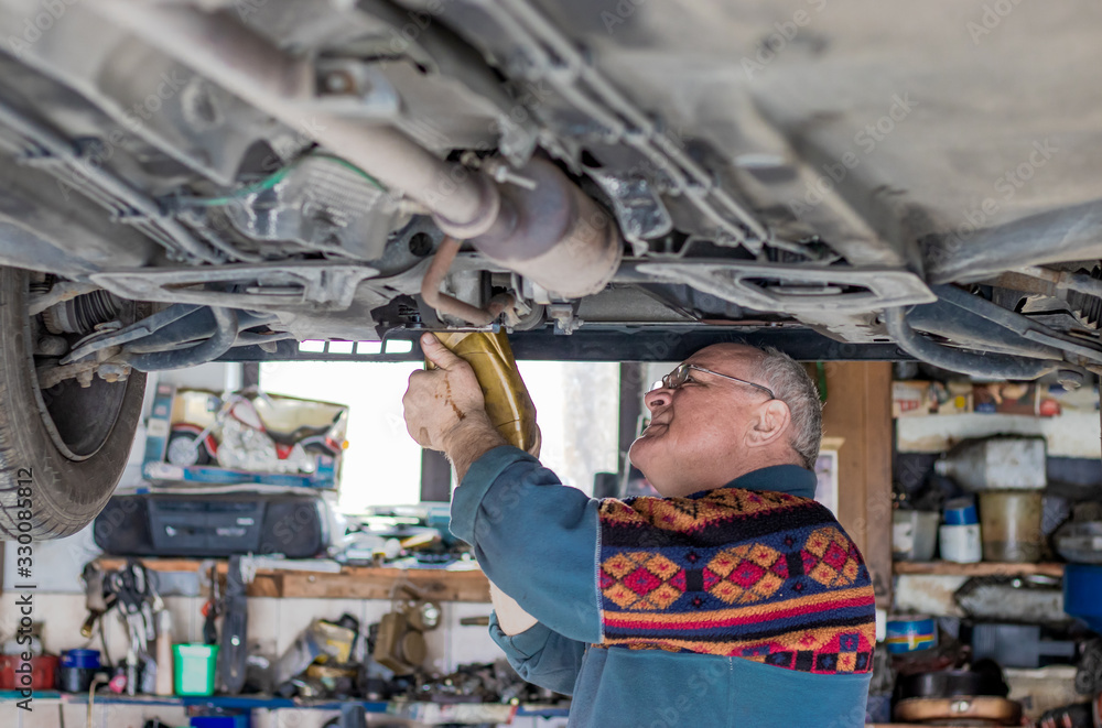 Panoramic shot of an old car mechanic checking and repairing a lifted