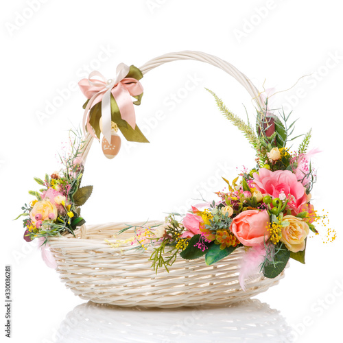 A very nice round white Easter basket with a bow on the handle and a variety of flowers. Decor in delicate pink and green colors.