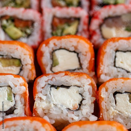 Closeup of sushi roll with salmon, avocado and cheese. Japanese cuisine restaurant. Background with sushi