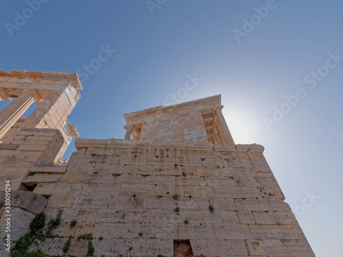 Athens Greece, Athena Nike (victorious) small temple with ionian style columns, standing by the entrance of Acropolis under crystal clear blue sky and sun halo