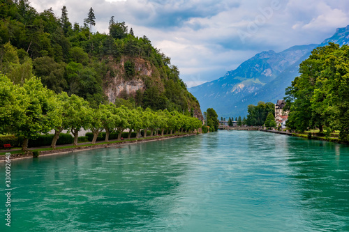 City park along the bank of Aare river in Old City of Interlaken, important tourist center in the Bernese Highlands, Switzerland.