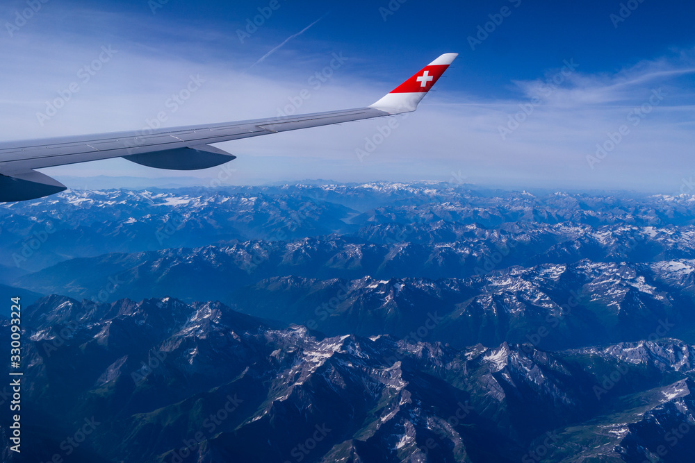 Airplane wing and wing tip flying over mountain landscape sunny day slight overcast Airplane wing and wing tip flying over mountain landscape sunny day slight overcast