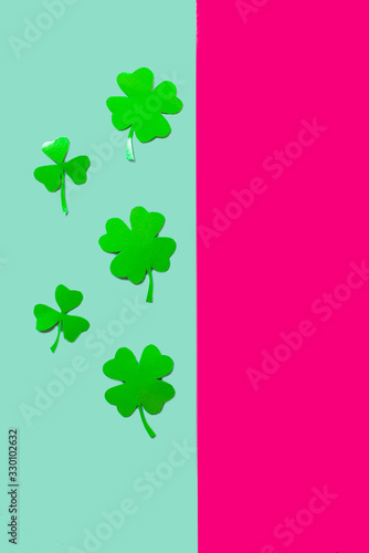 Five green clovers on a blue and rose background  flat lay  copy text  vertical separation.