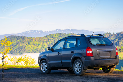 suv on the edge of a mountain. beautiful view in to the distant valley full of fog. ridge in the distance. fantastic springtime scenery in the morning. travel by car concept © Pellinni