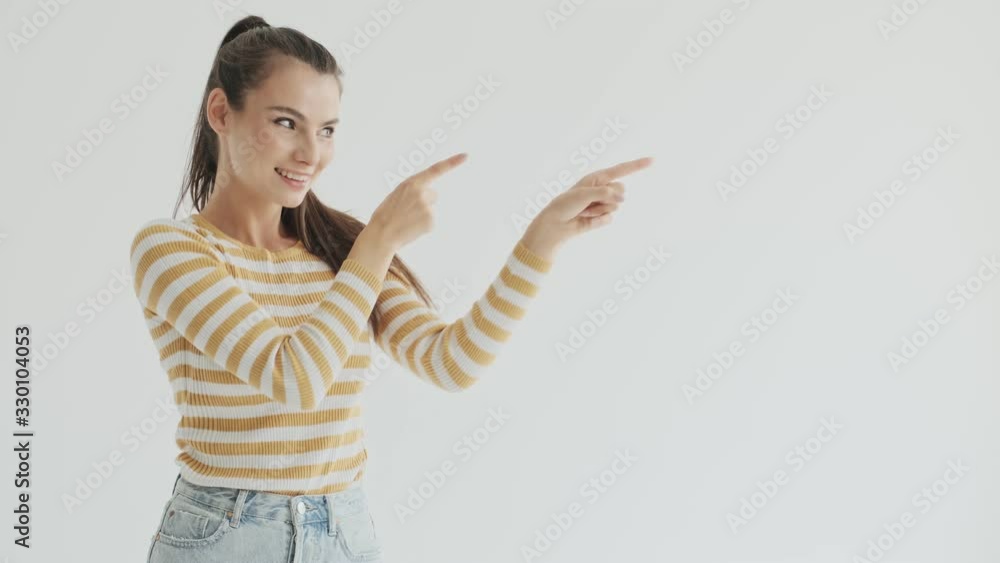 A smiling funny young woman is pointing to the side isolated over white background in studio A smiling funny young woman is pointing to the side isolated over white background in studio
